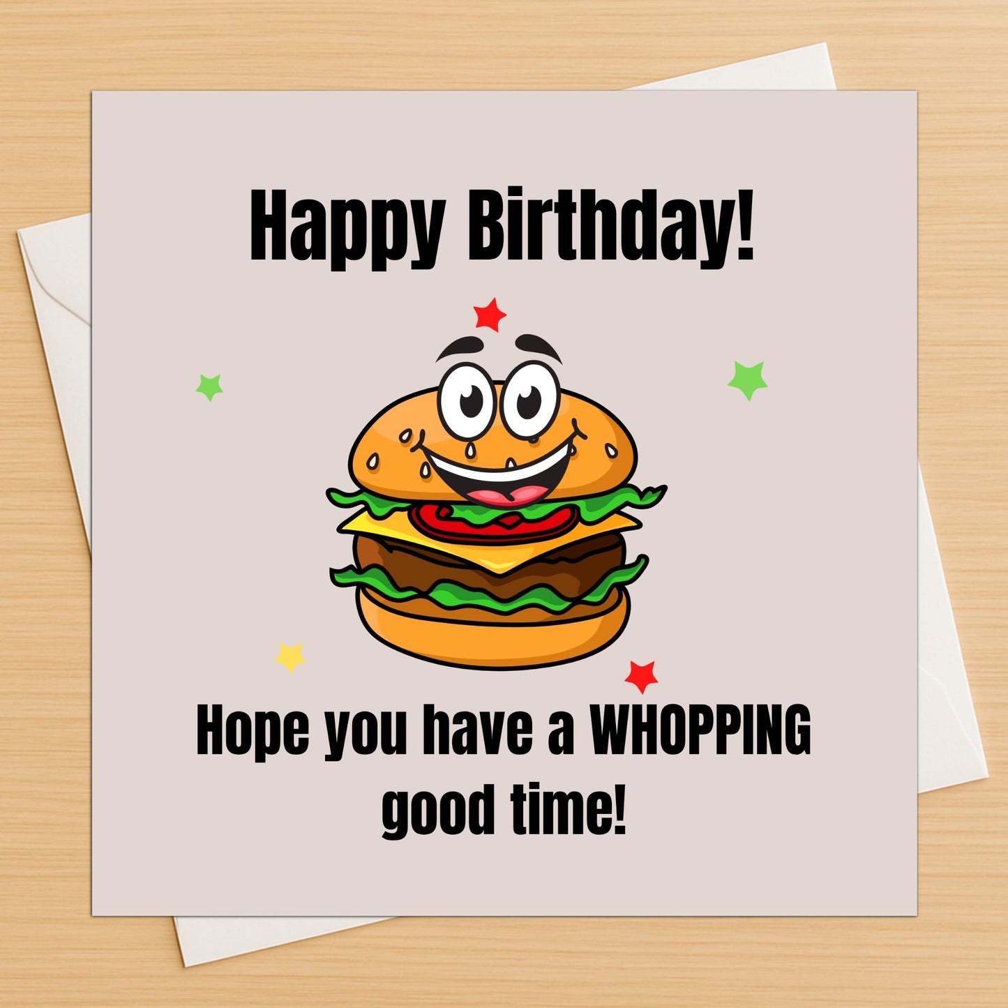 Funny burger birthday card lying flat on a wooden table with white envelope