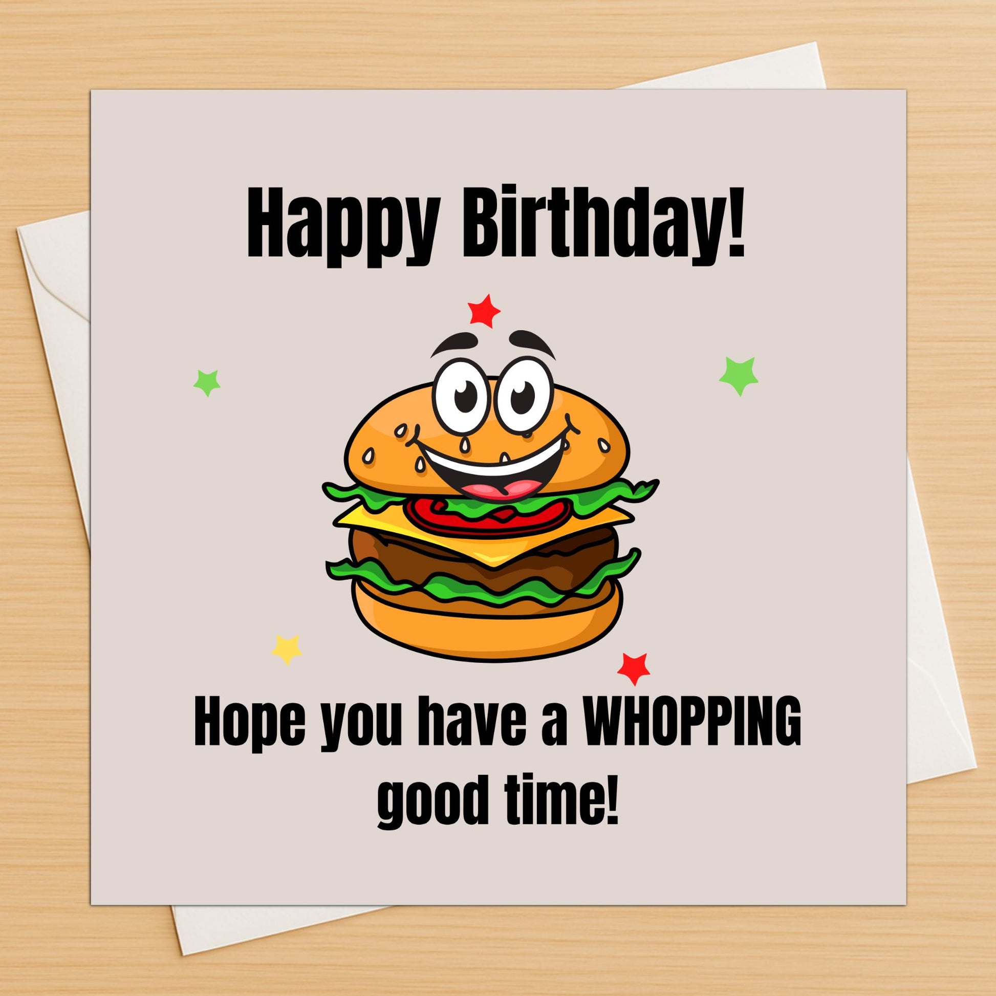 Funny burger birthday card lying flat on a wooden table with white envelope