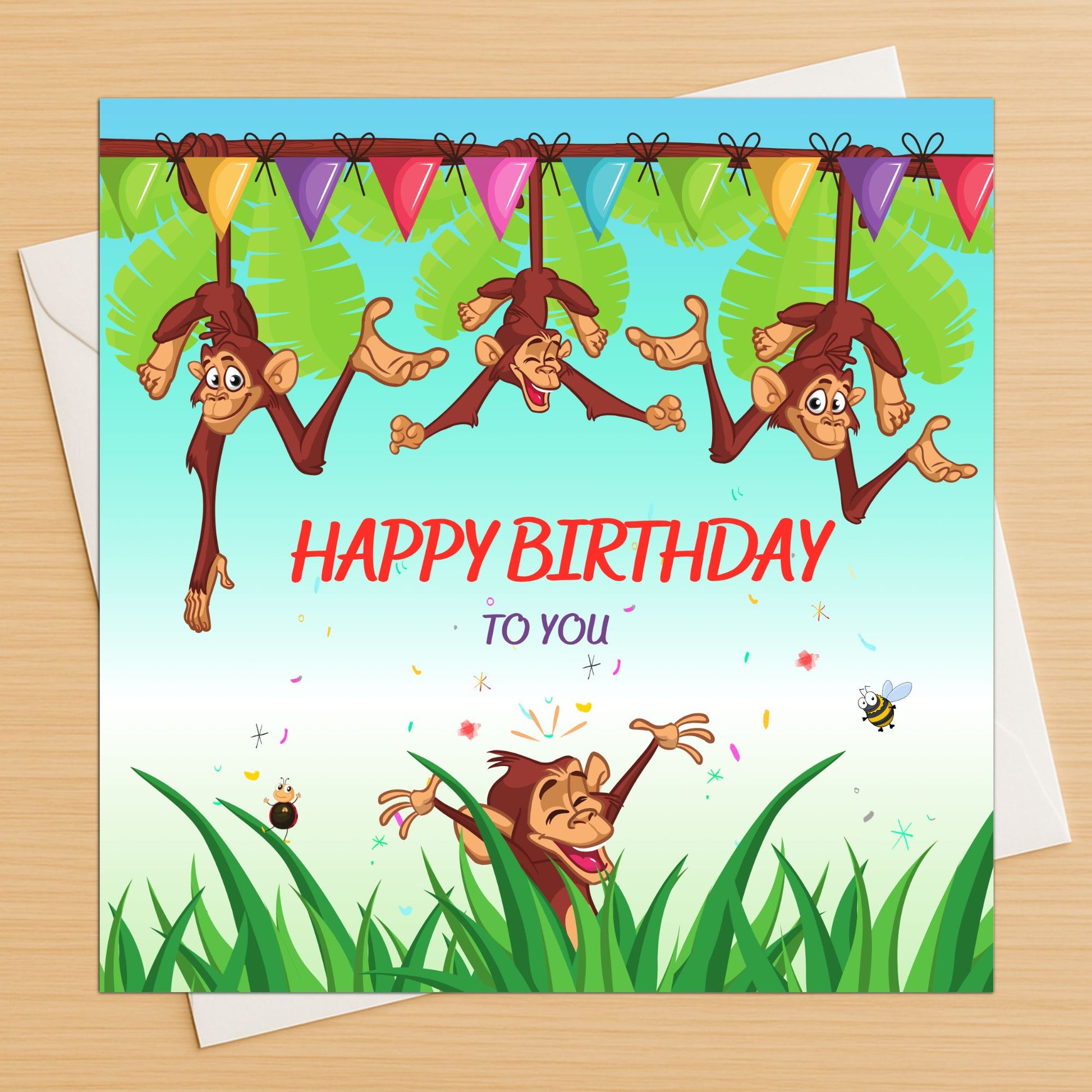 Funny monkeys birthday card with colourful jungle design on wooden table