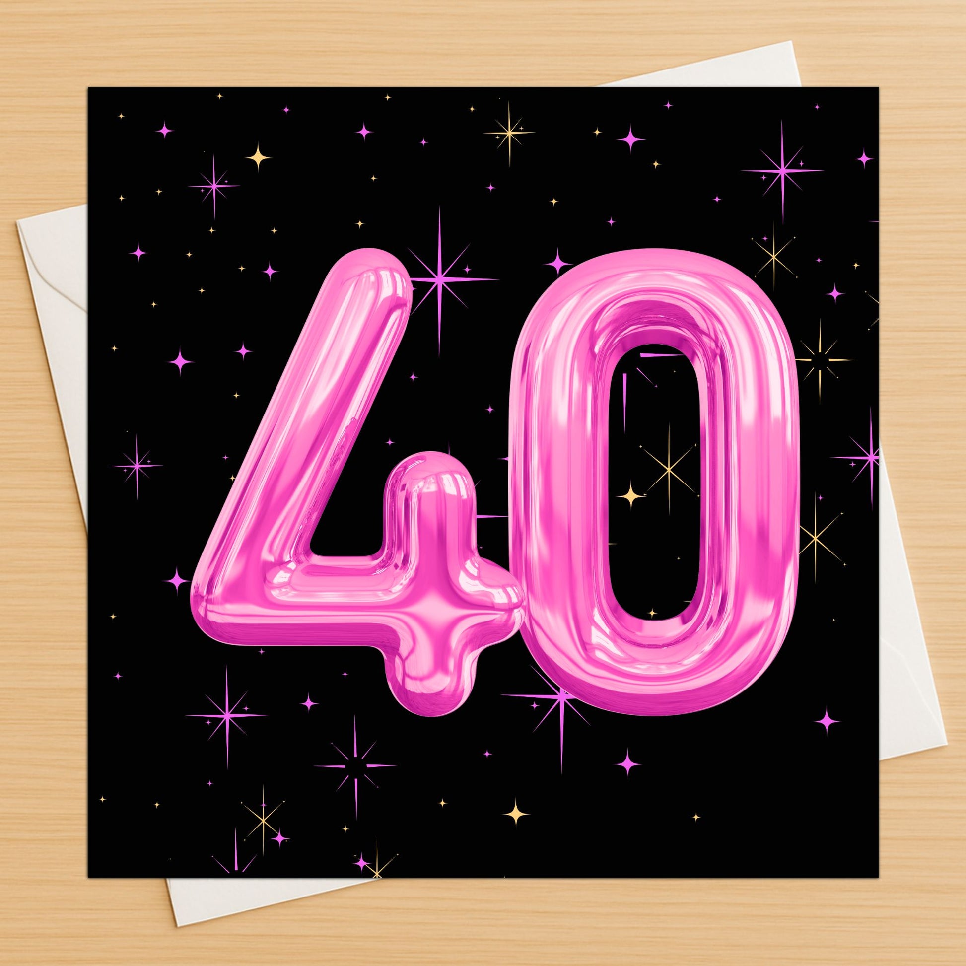 Card with pink number '40' balloons on a black background with stars, on a wooden surface.