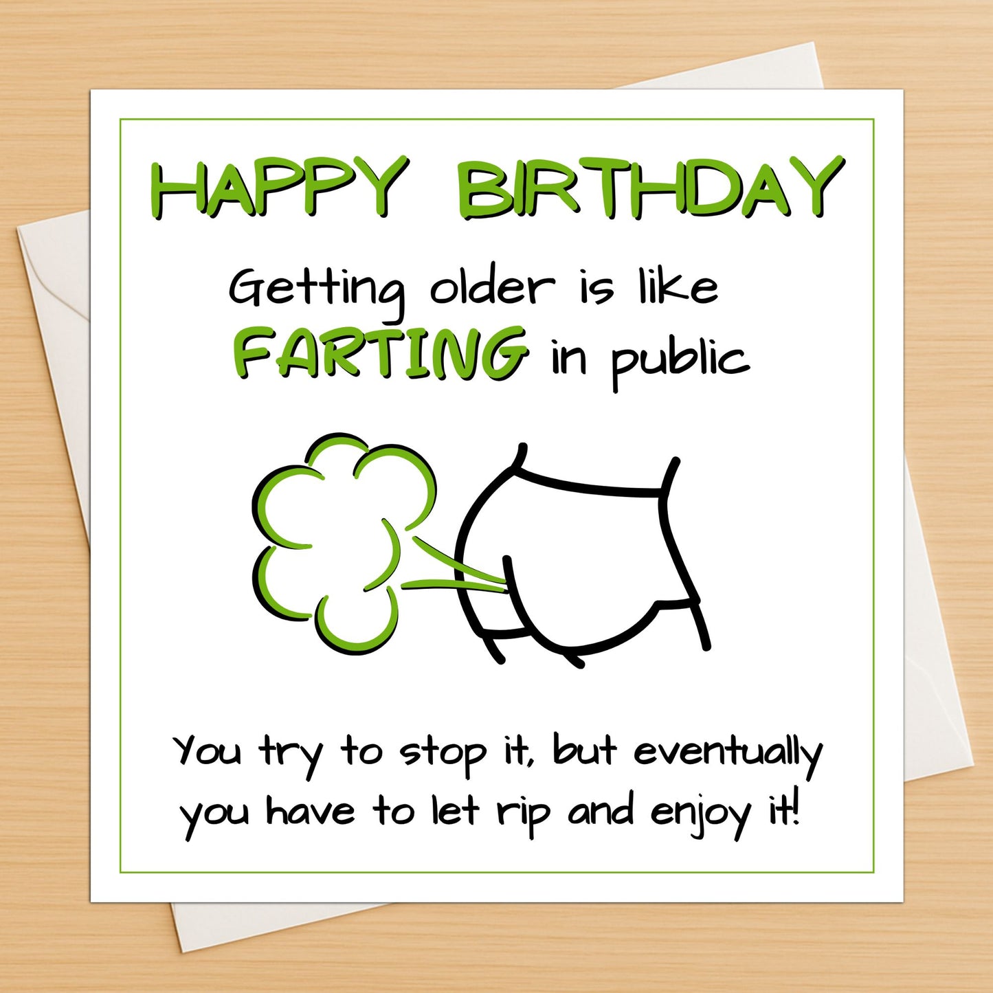 Rude fart joke birthday card lying flat on a wooden table with white envelope