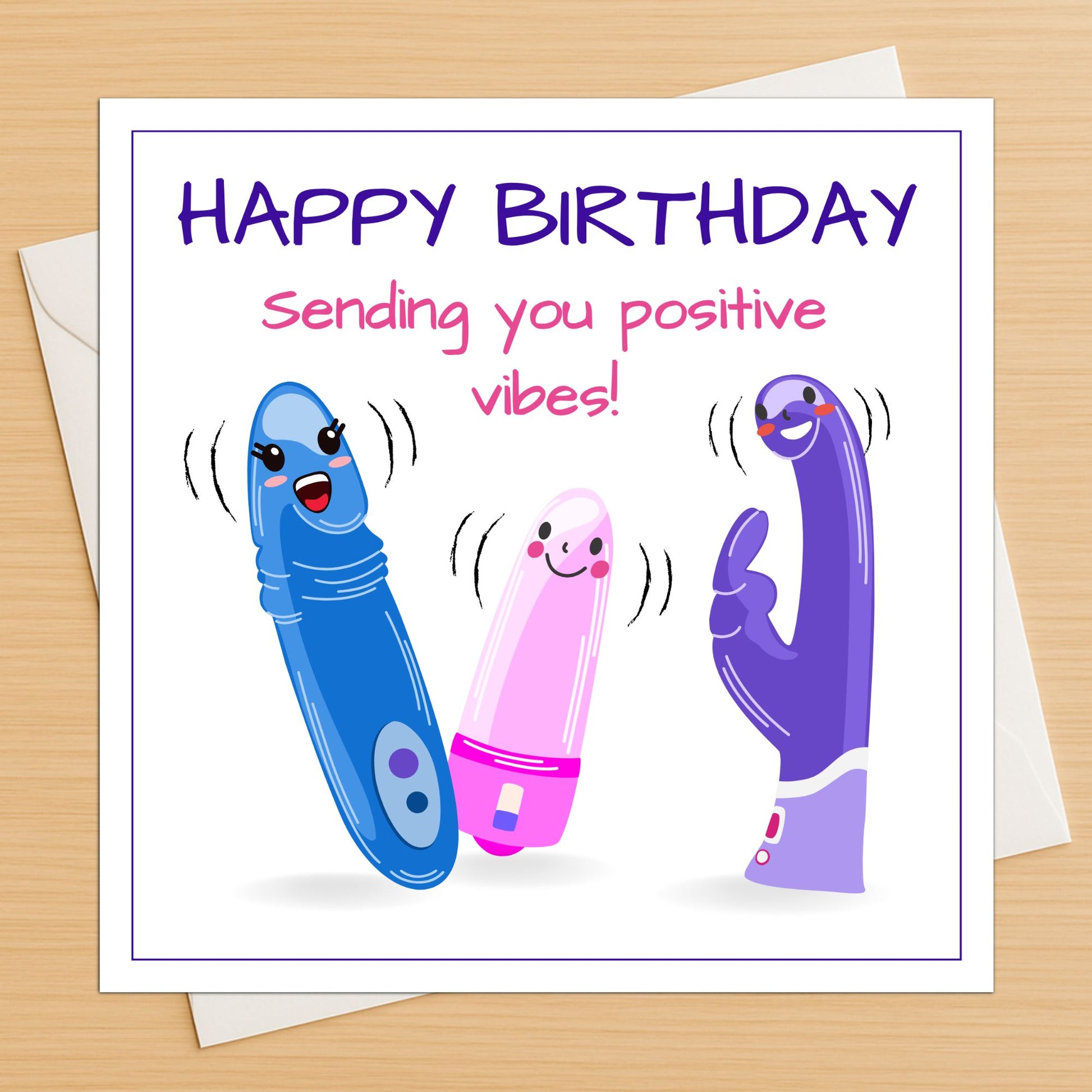 Rude vibrator funny birthday card lying flat on a wooden table with white envelope